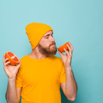 bearded-european-man-yellow-shirt-isolated-smelling-delicious-grapefruit-with-closed-eyes