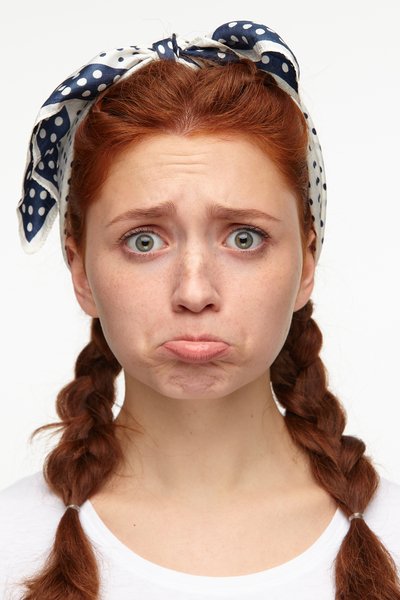 indoor-portrait-of-young-ginger-female-posing-over-white-background-starring-into-camera-with-sad-depressed-facial-expression