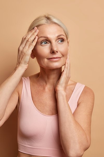 portrait-mature-elderly-european-woman-touches-face-gently-has-perfect-skin-looks-thoughtfully-away-enjoys-her-soft-complexion-cares-about-appearance-satisfied-after-anti-aging-procedure