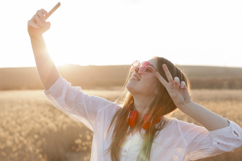 side-view-carefree-woman-with-sunglasses-taking-selfie-nature