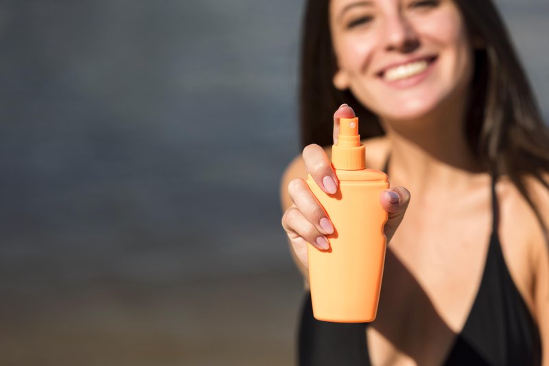 smiley-woman-holding-sunscreen-beach-with-copy-space